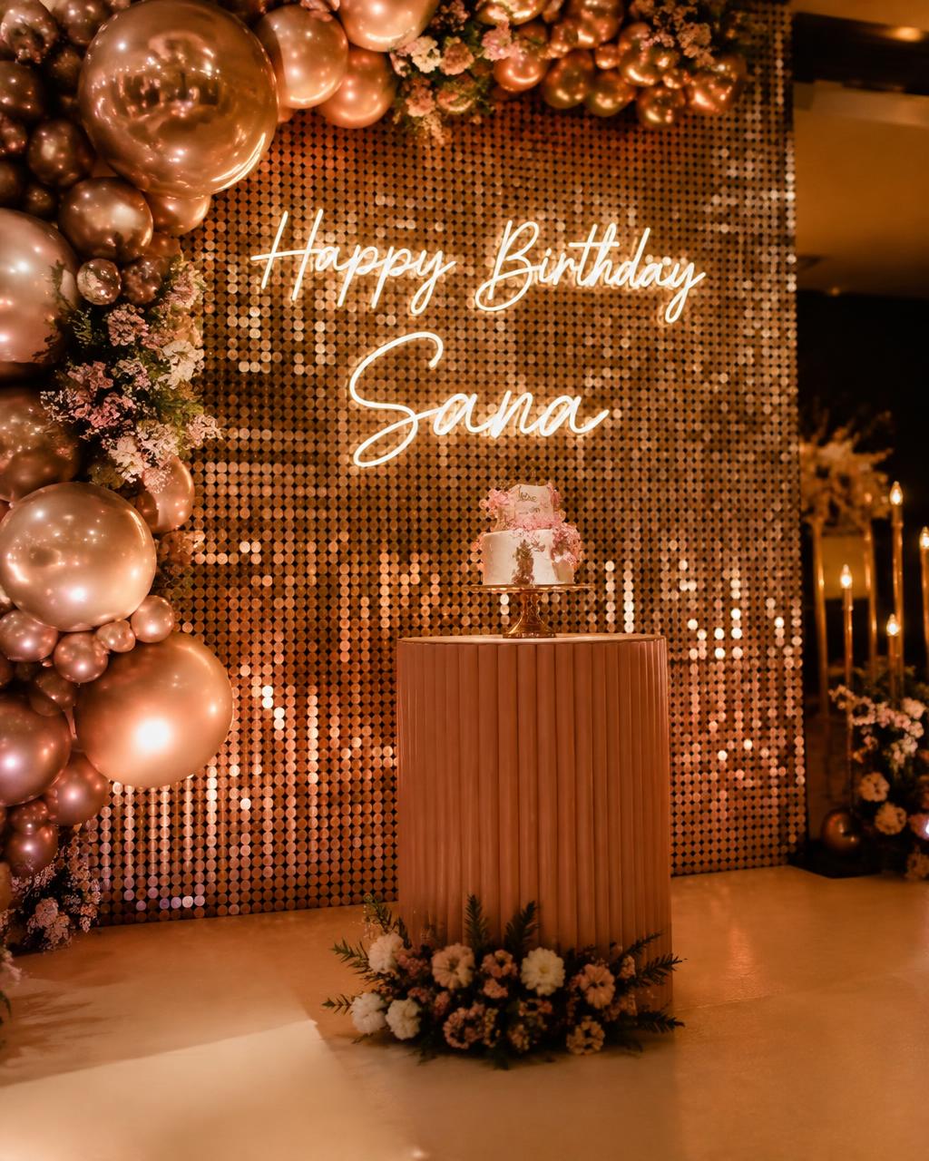 Shimmer wall birthday backdrop with rose gold balloons and cake display